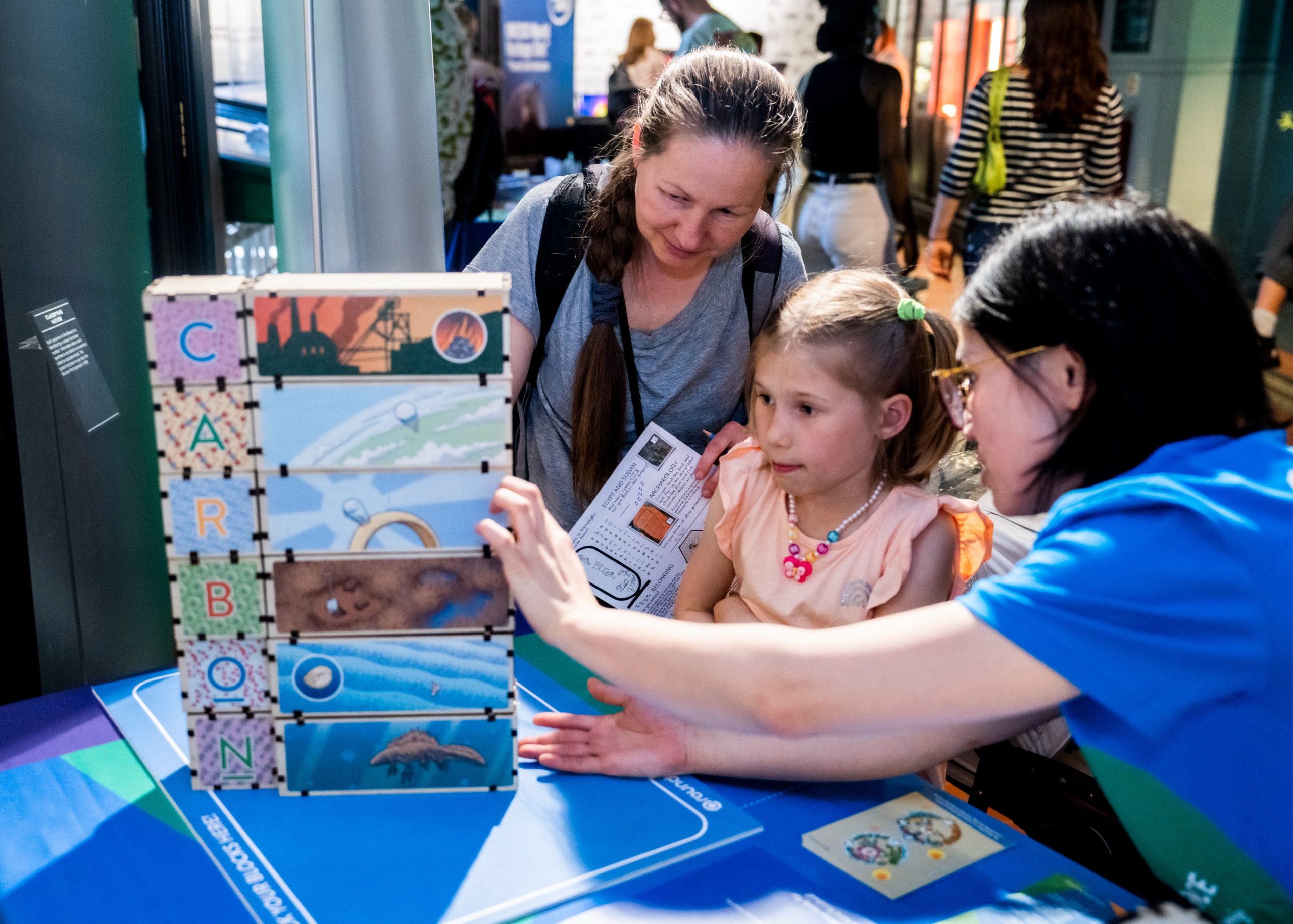 young child and two adults stack letter blocks in 3-d learning game